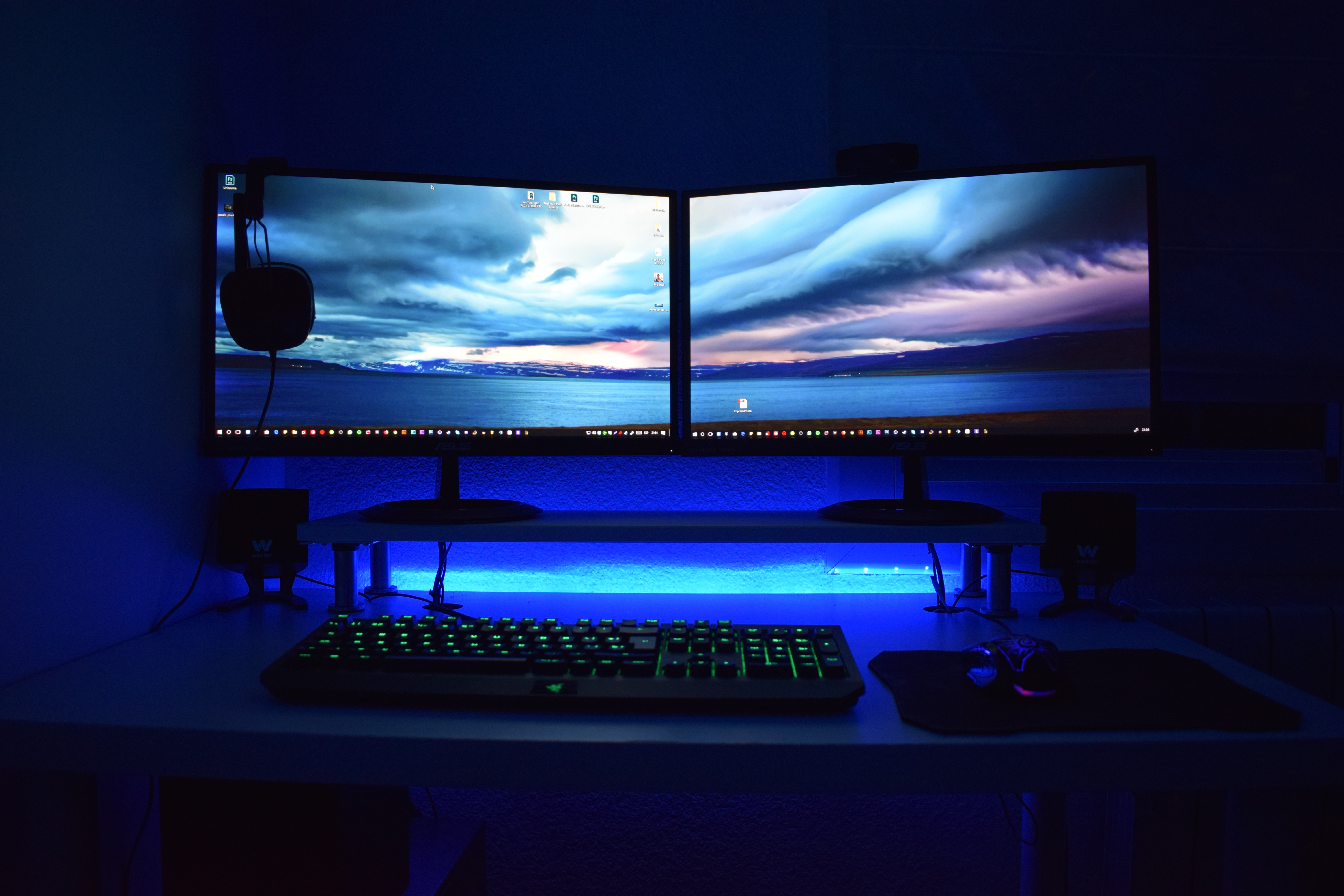 Imagem de uma mesa com teclado, mouse e dois monitores ligados.